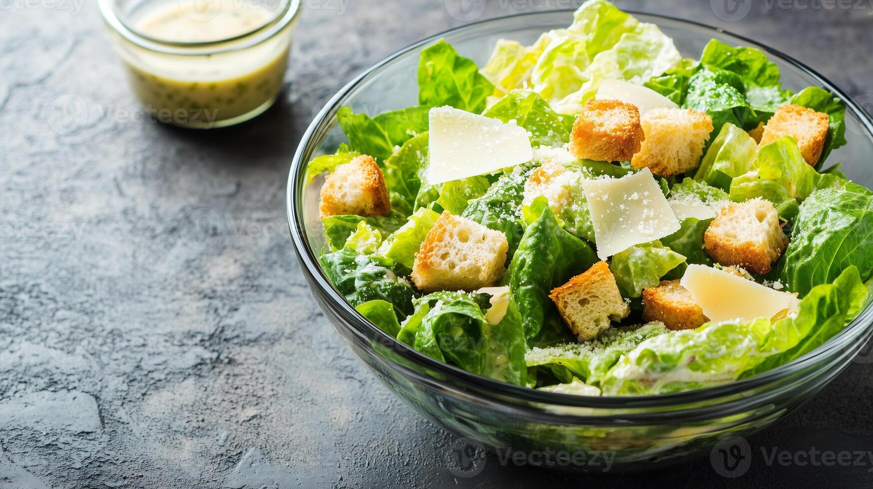 Caesar salad served in a glass bowl with romaine lettuce, croutons, parmesan, and dressing, food setting photo