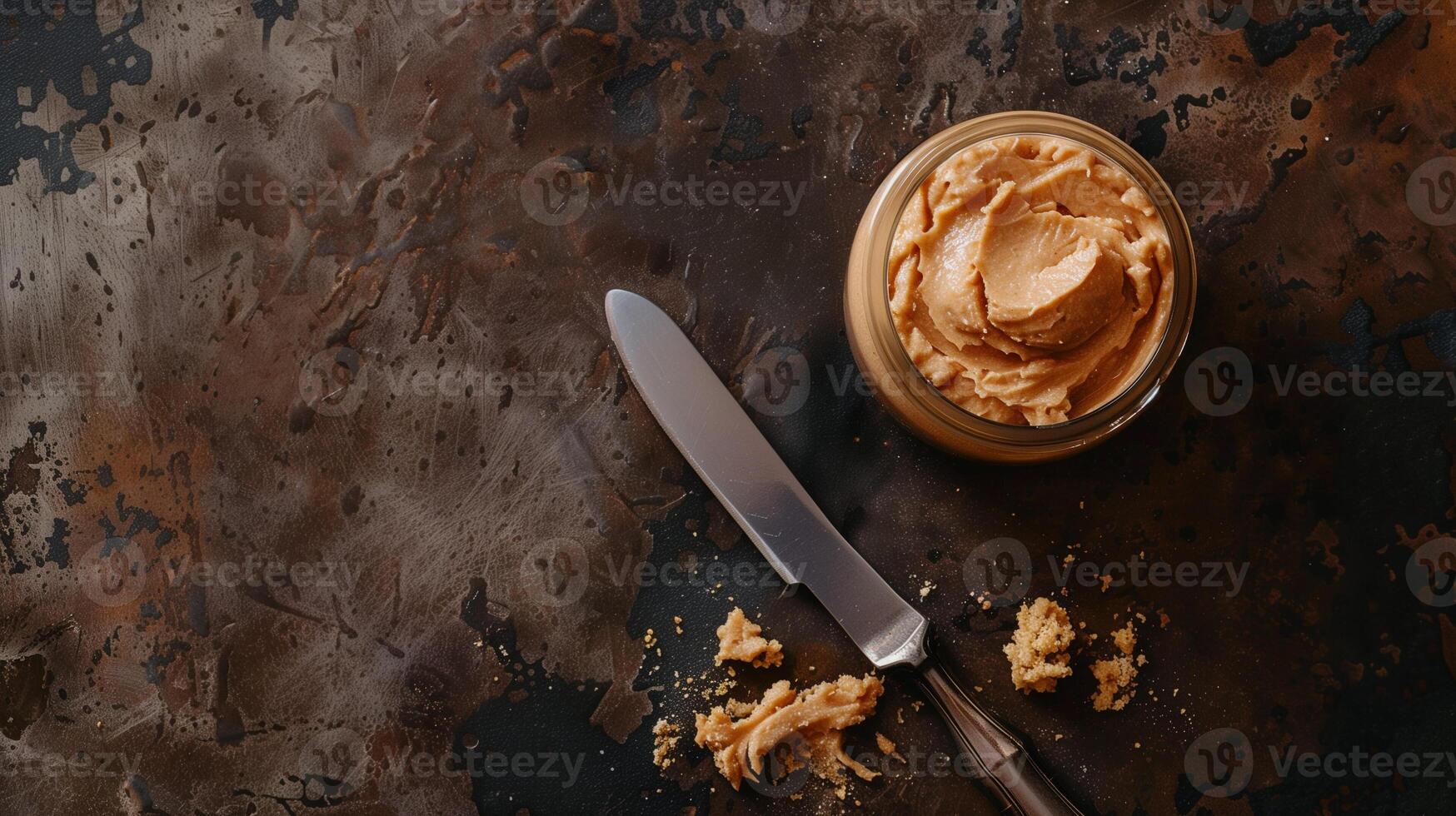 Top-down view of jar of hazelnut spread next to spreading knife on wooden table, culinary photography photo