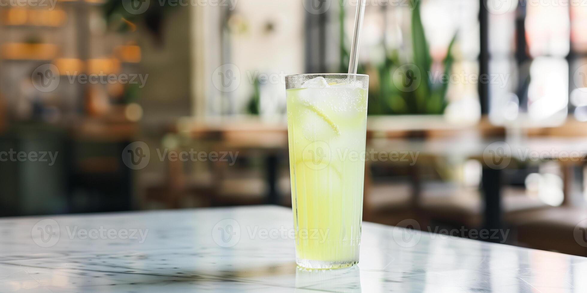 Tall glass with a straw, containing a light green liquid, placed on a marble table, food setting photo