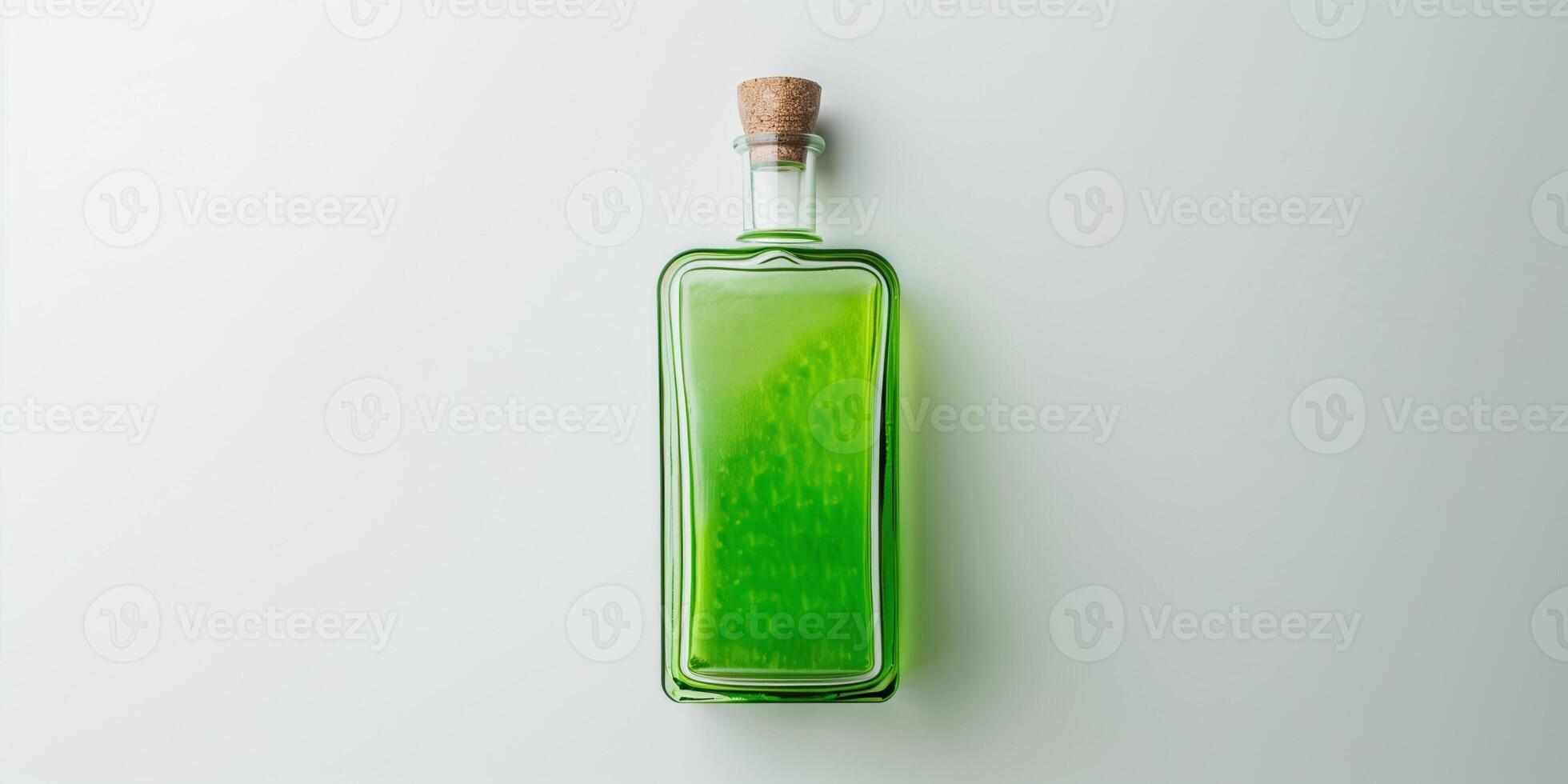 Transparent bottle containing a green liquid, positioned upright on a plain white background, food setting photo