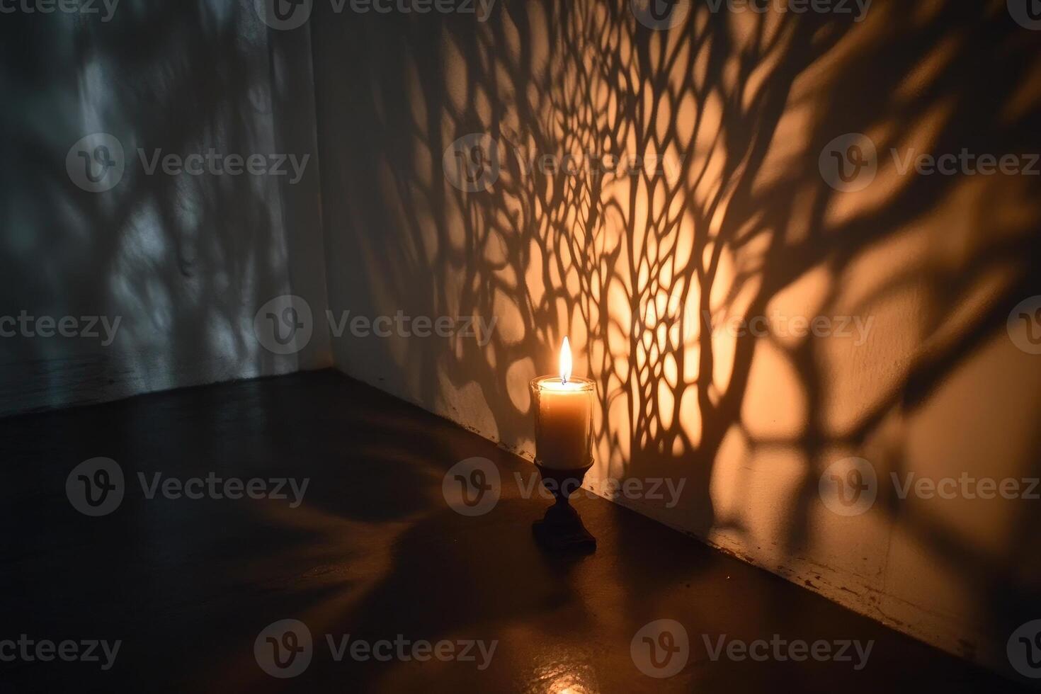 A Single Lit Candle Casting a Tree-Like Shadow on a Wall photo