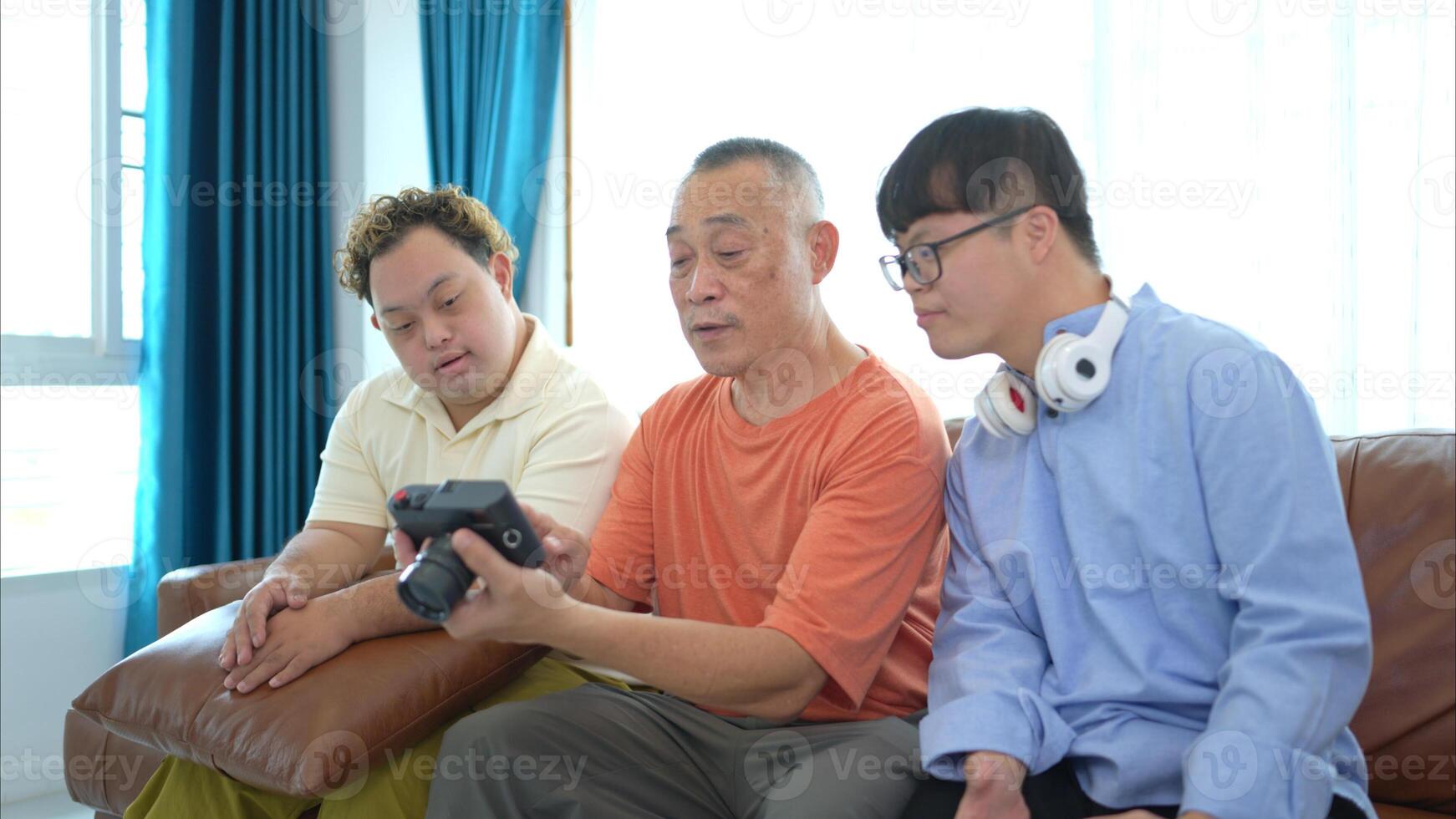On their day off, the grandfather and grandson look at old photos on camera in living room of house