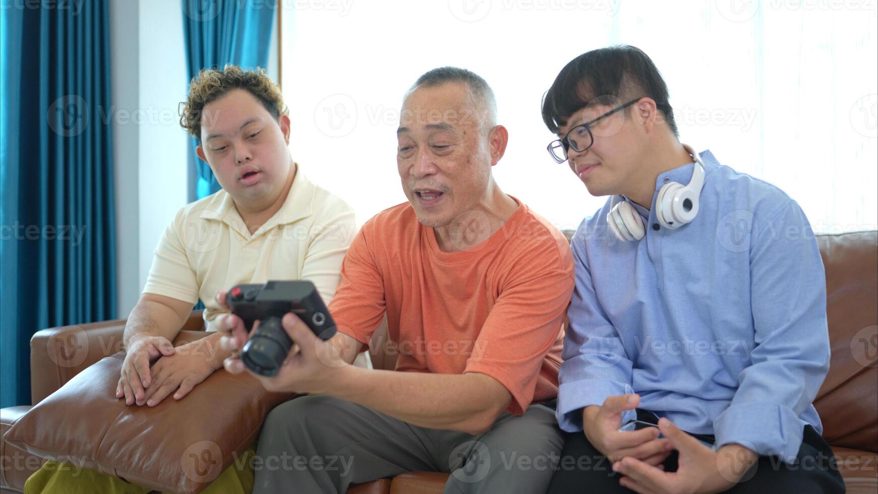 On their day off, the grandfather and grandson look at old photos on camera in living room of house
