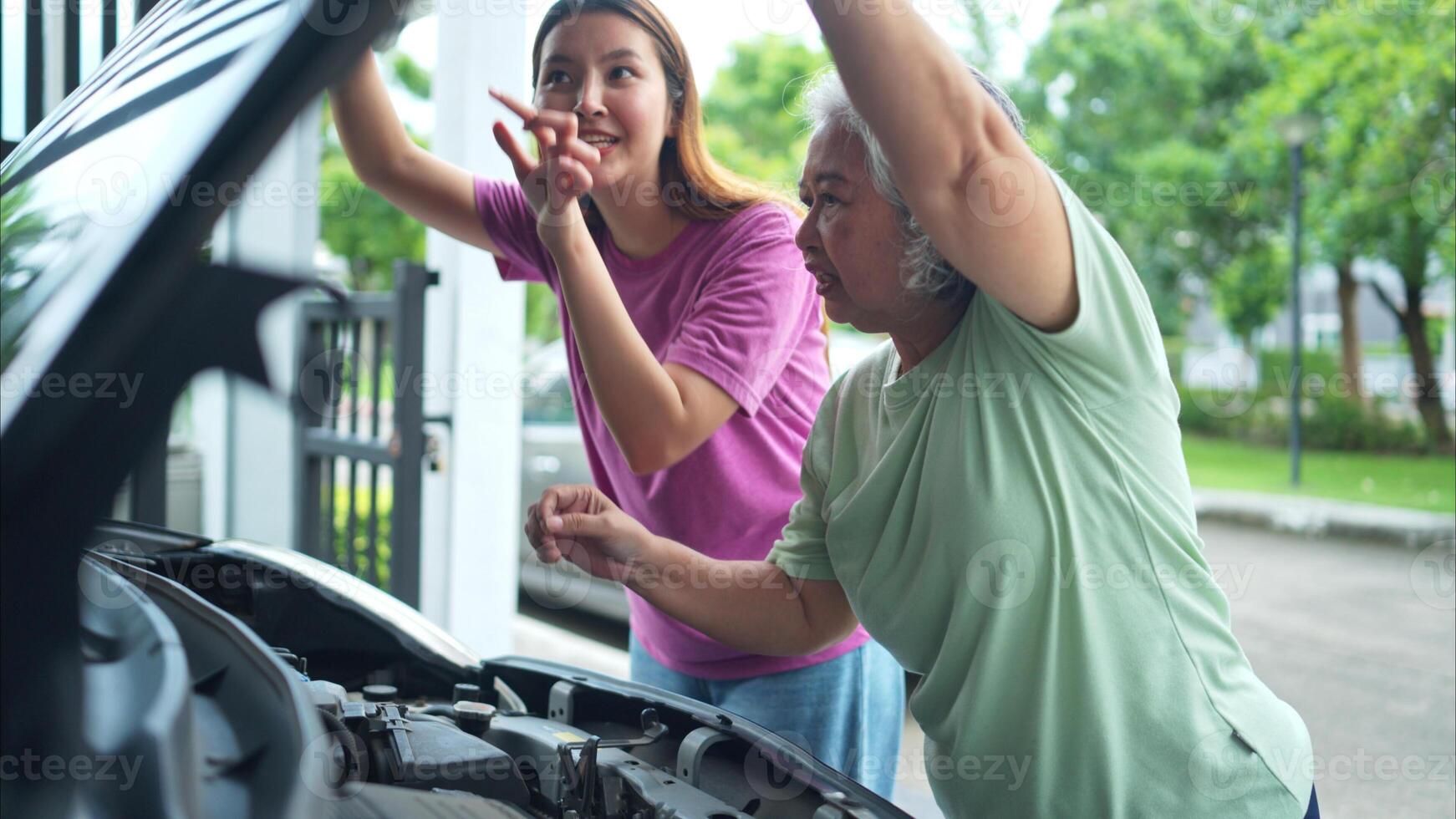 Grandmother and grandchild help each other execute a basic engine check on their parents' automobile photo