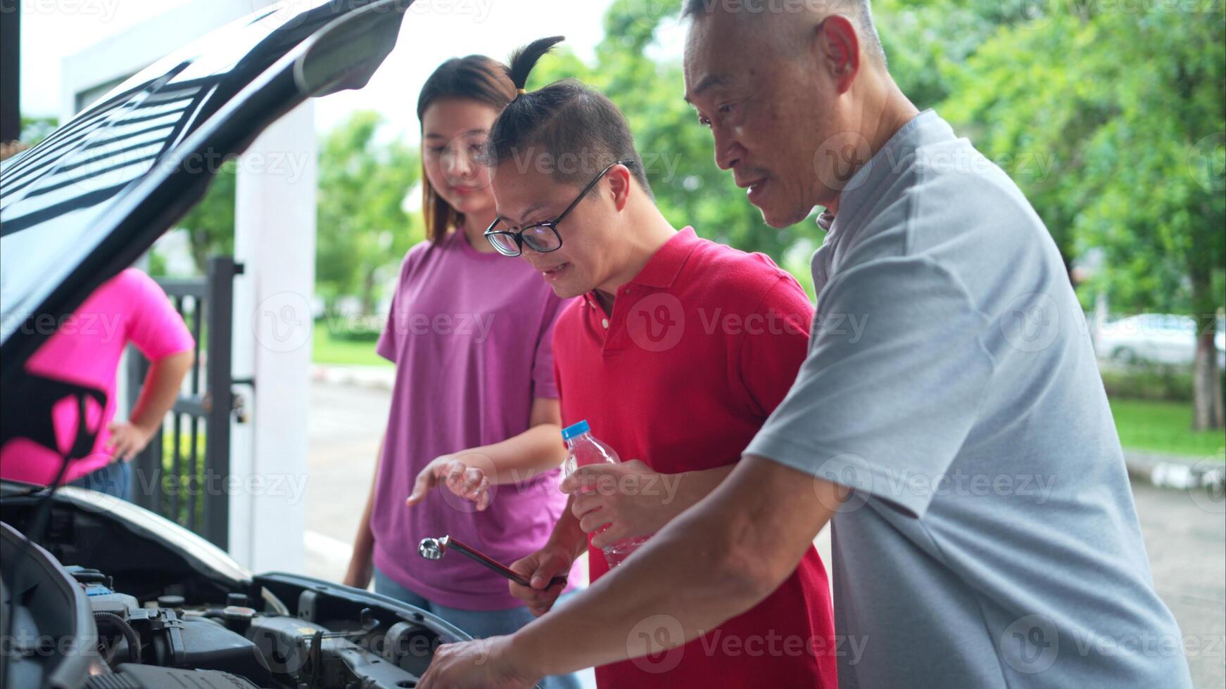 A brother and sister help each other execute a basic engine check on their parents' automobile photo