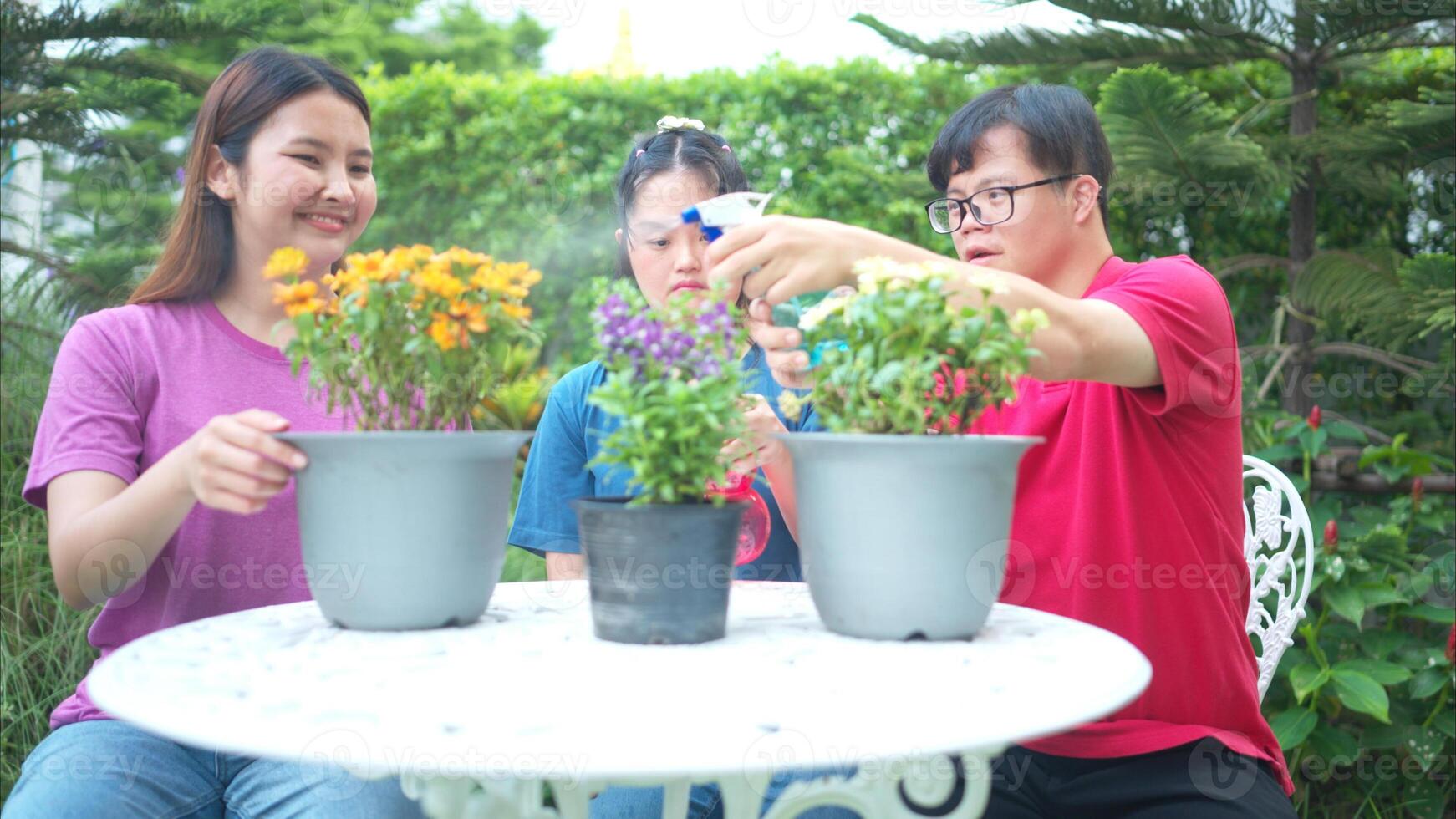 On their day off, Three siblings help water and plant flowers in the front yard photo