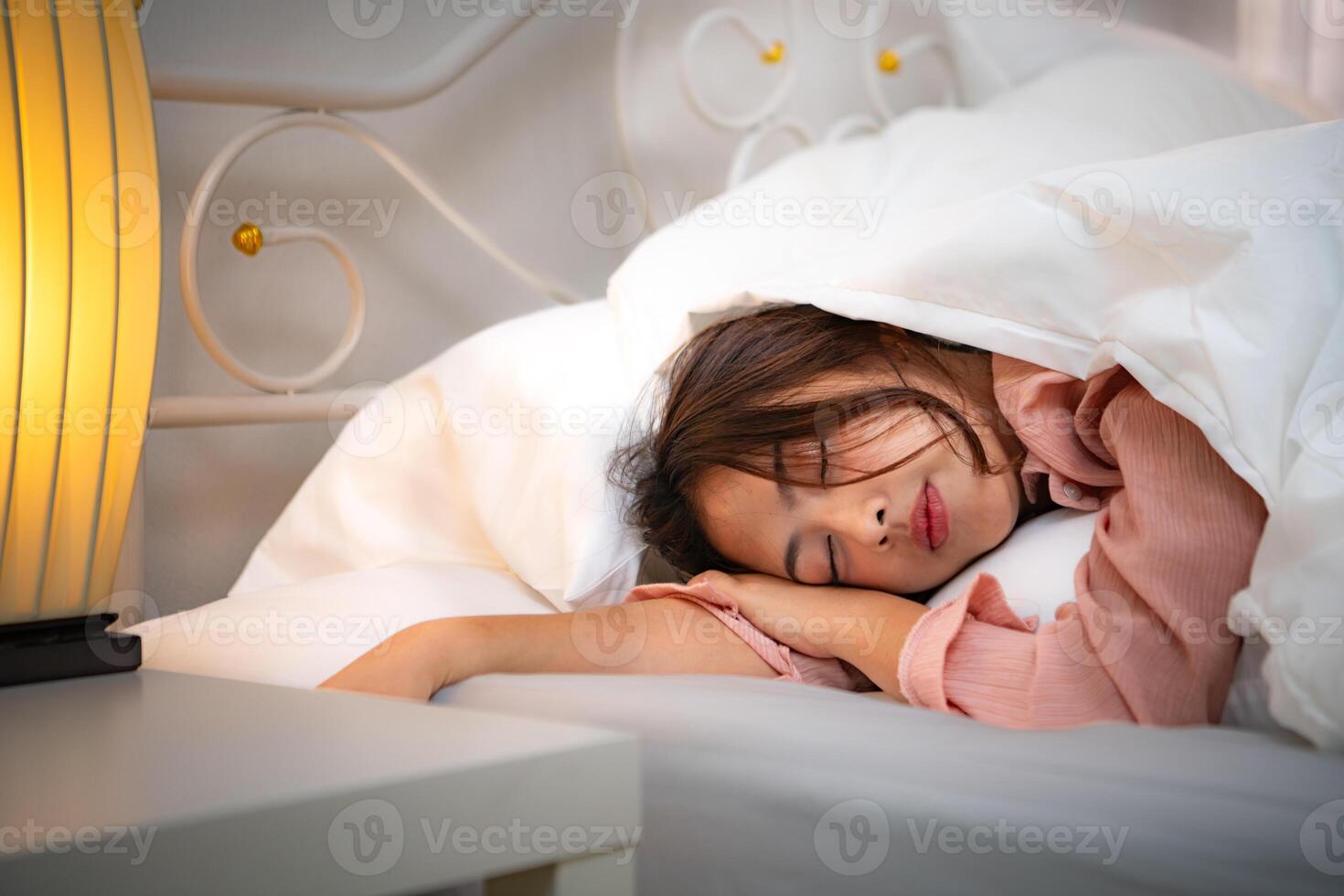 Asian young woman on the bed in the bedroom trying to wake up and prepare for work photo