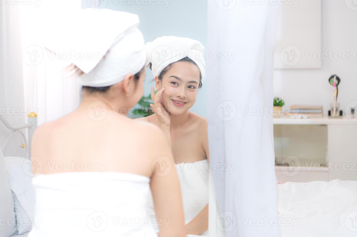 Asian young woman with towel wrapped on head and body applying makeup after shower, Morning beauty routine before work photo