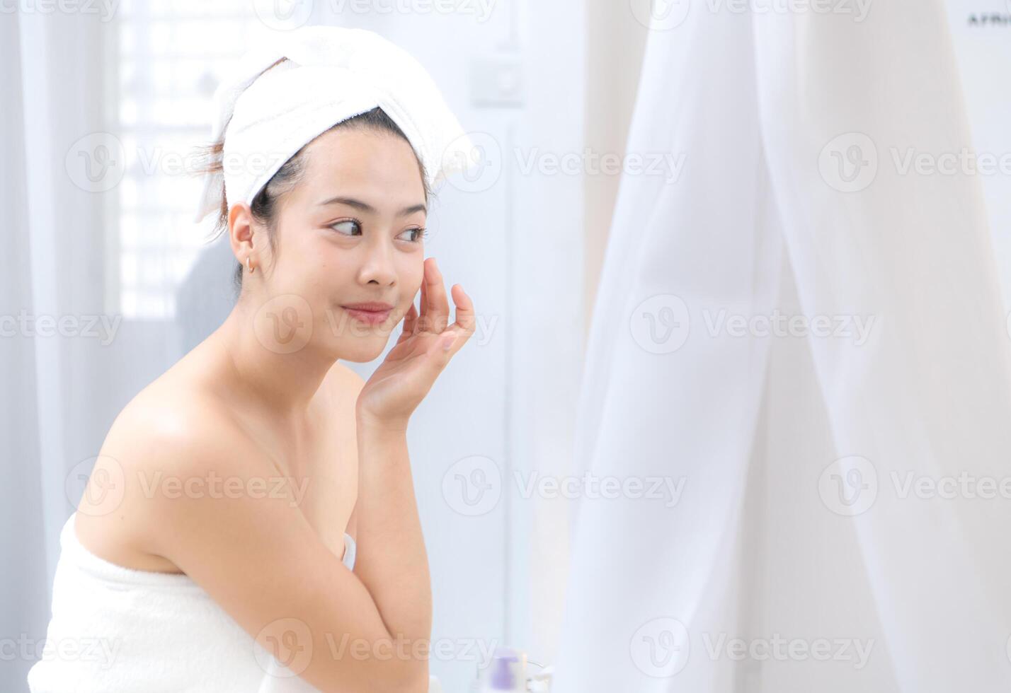 Asian young woman with towel wrapped on head and body applying makeup after shower, Morning beauty routine before work photo