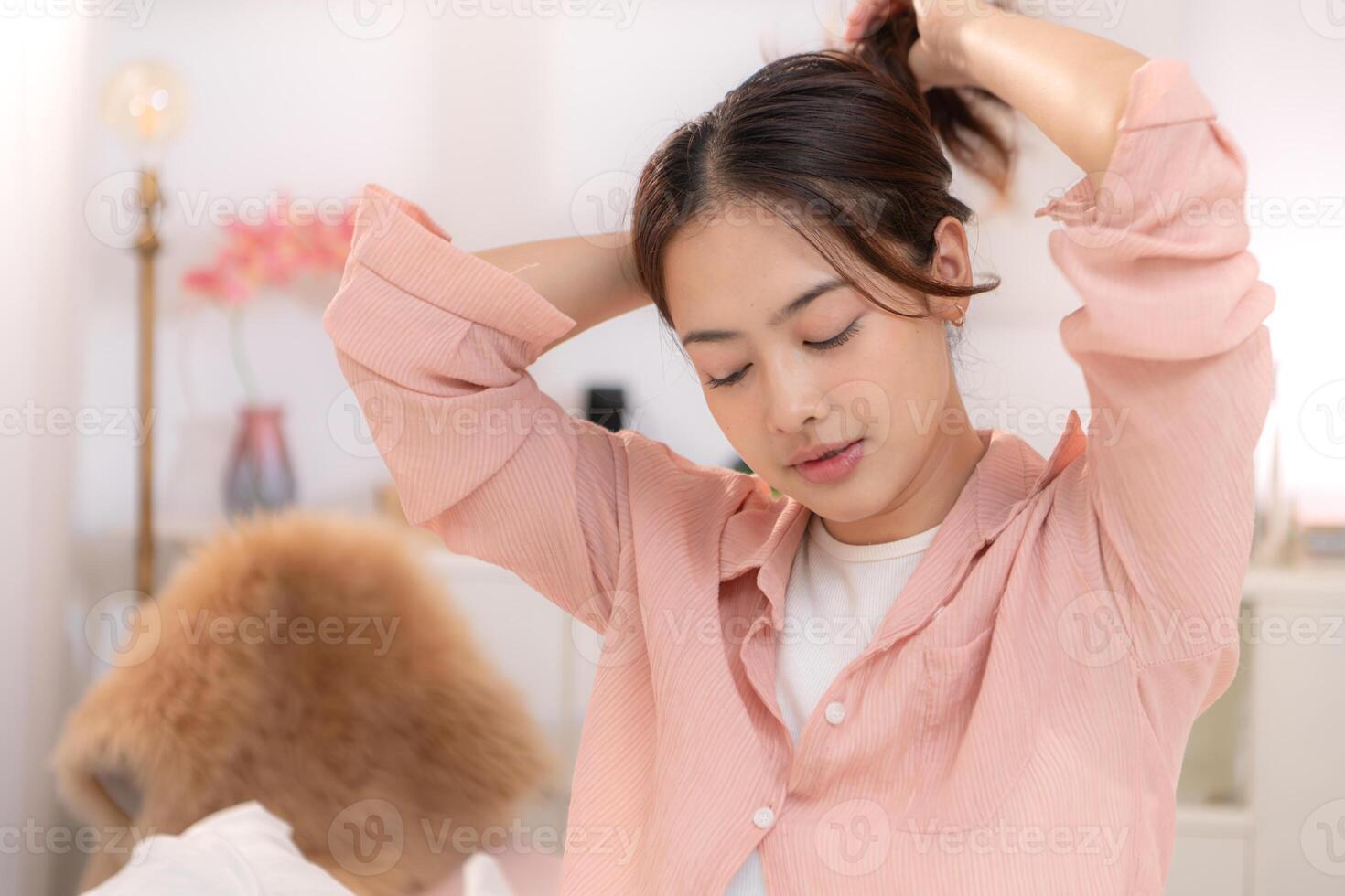 Asian young woman in pink dress preparing for work, spraying perfume in dressing room photo