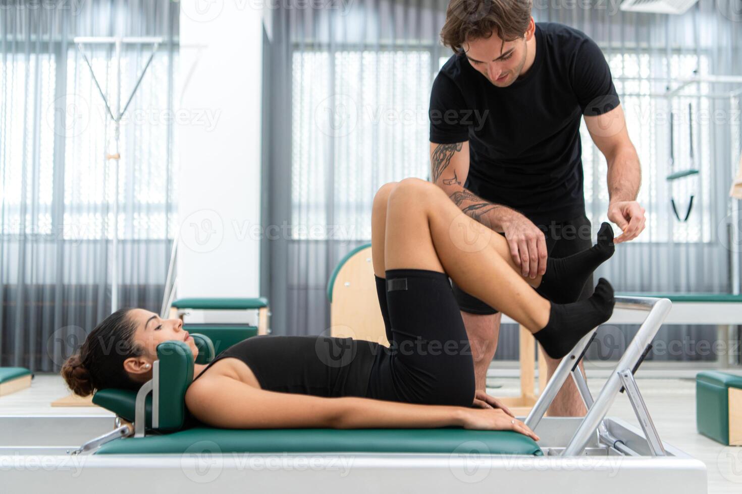 A young man and a young woman are doing pilates exercises on a pilates reformer photo