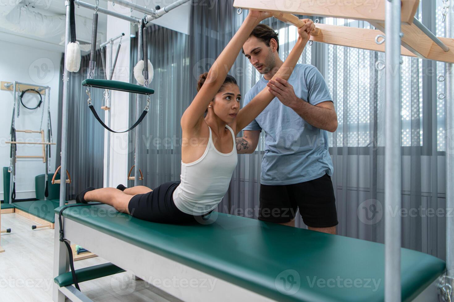 A young man and a young woman are doing pilates exercises on a pilates cadillac photo