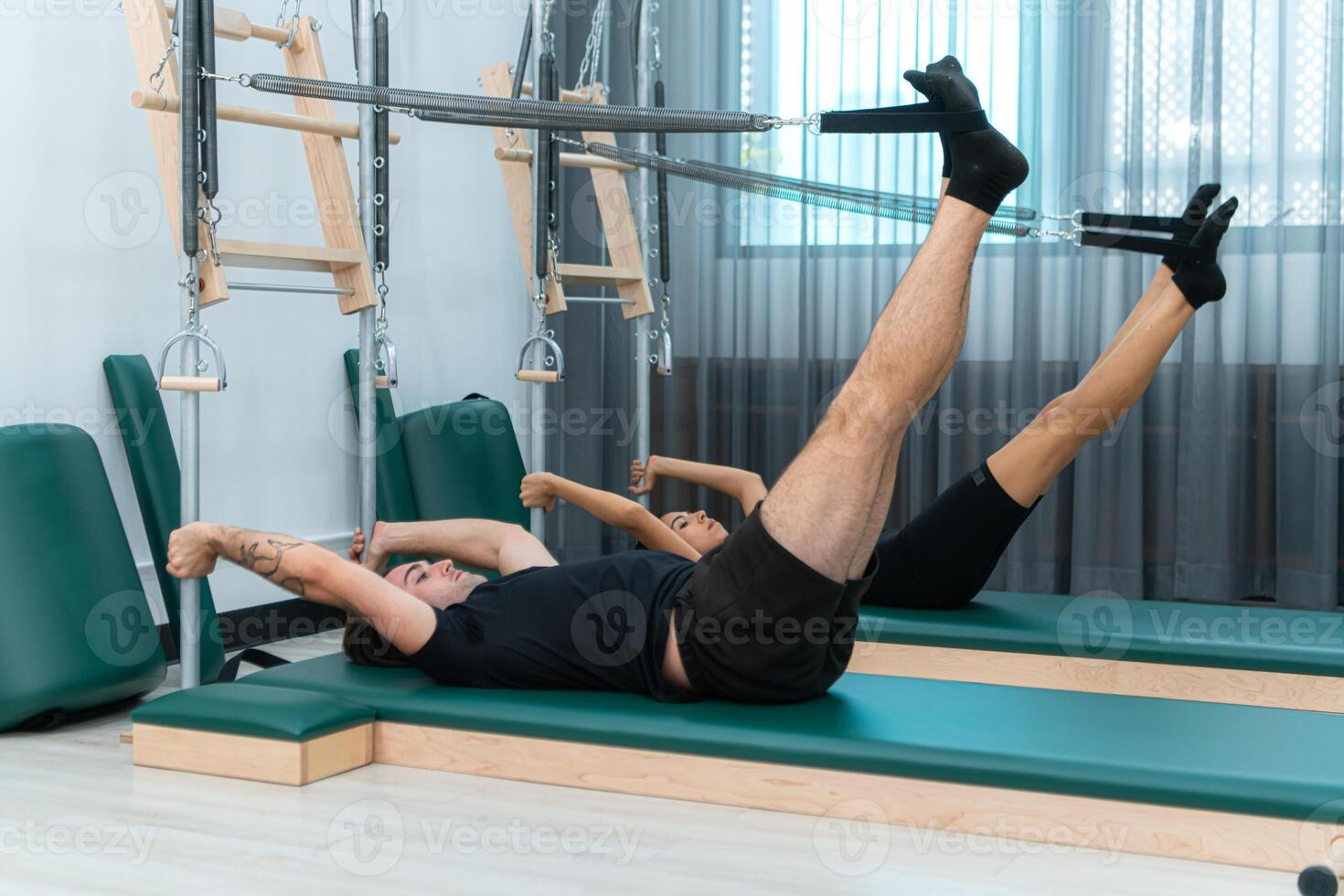 A young man and a young woman are doing pilates exercises on a pilates reformer photo