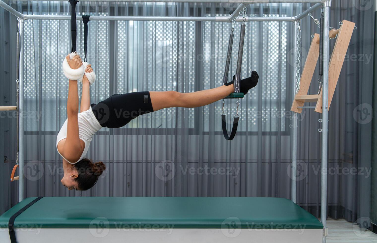 A young woman doing pilates exercises on a pilates cadillac photo