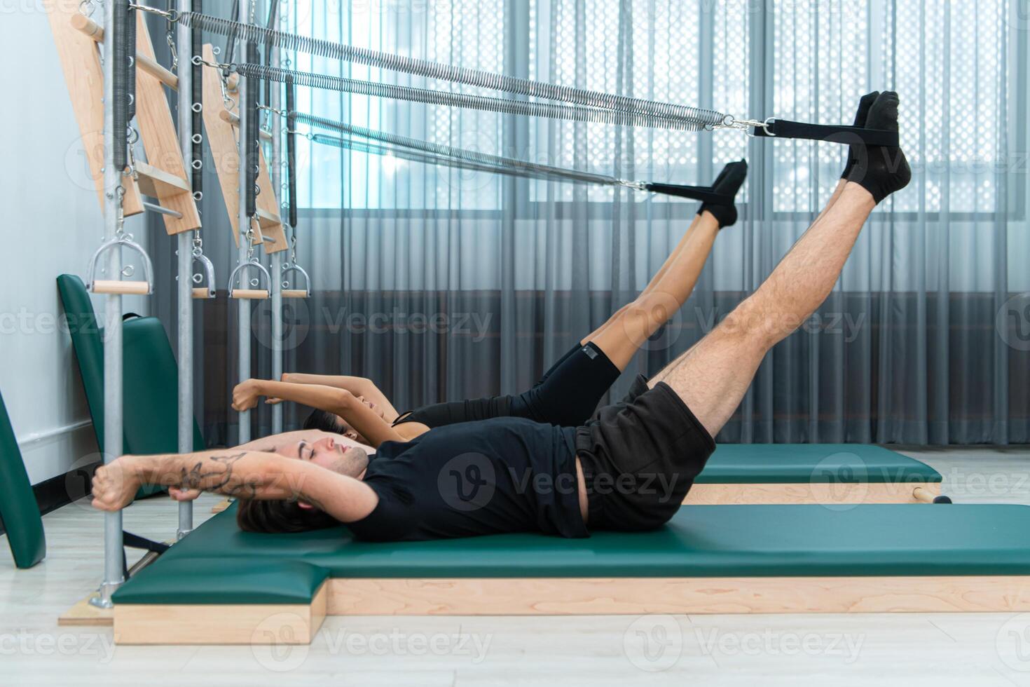 A young man and a young woman are doing pilates exercises on a pilates reformer photo