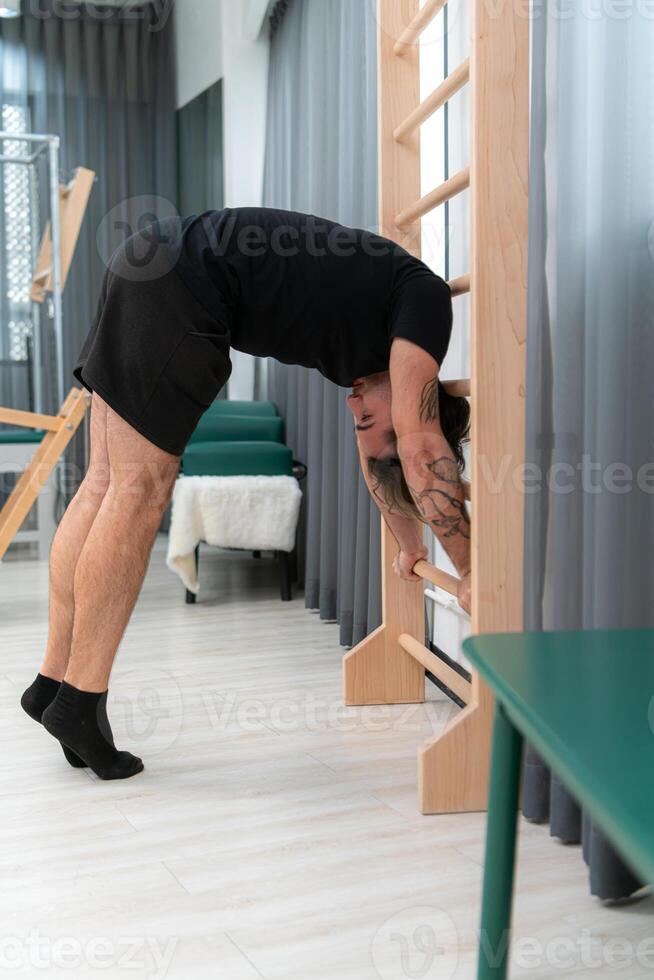 A young man doing cool down after pilates exercises class photo