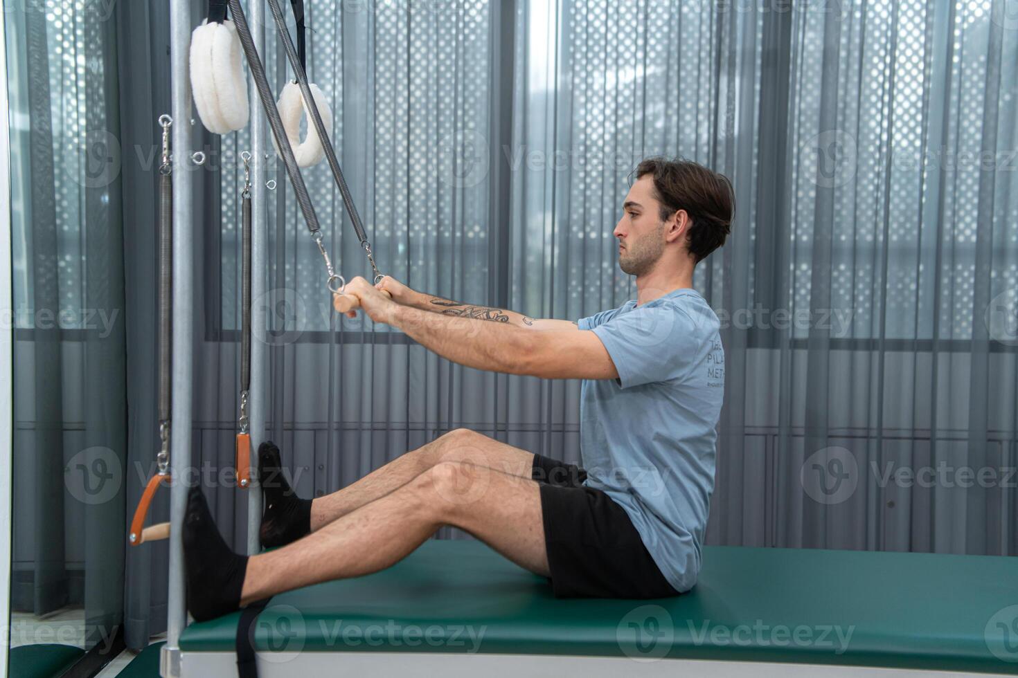 A young man doing pilates exercises on a pilates cadillac photo