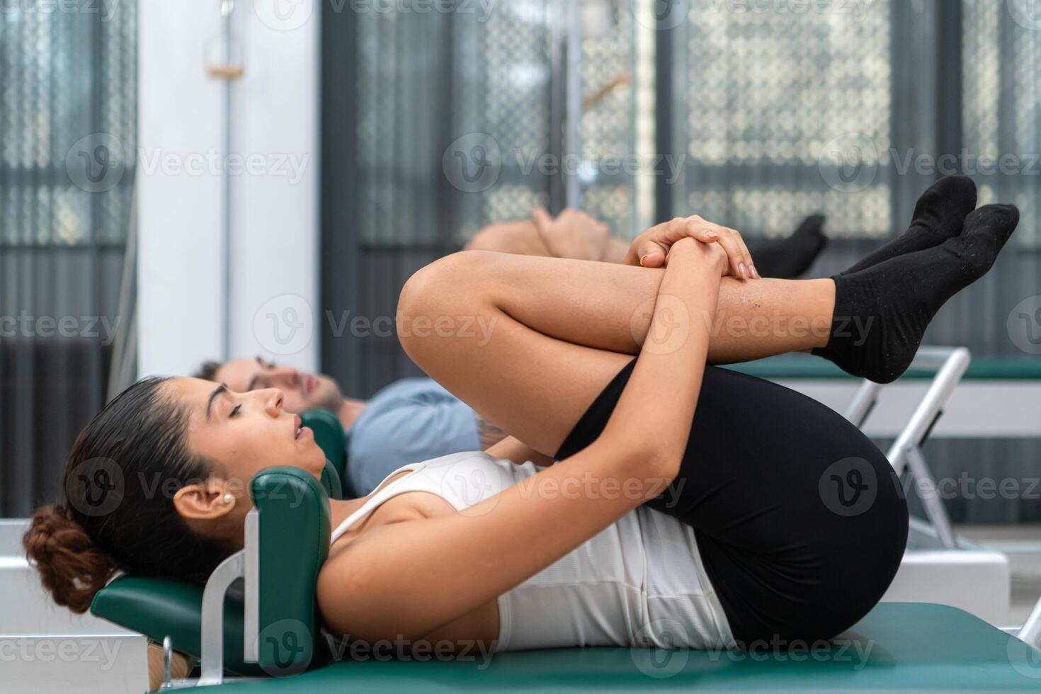A young man and a young woman are doing pilates exercises on a pilates reformer photo