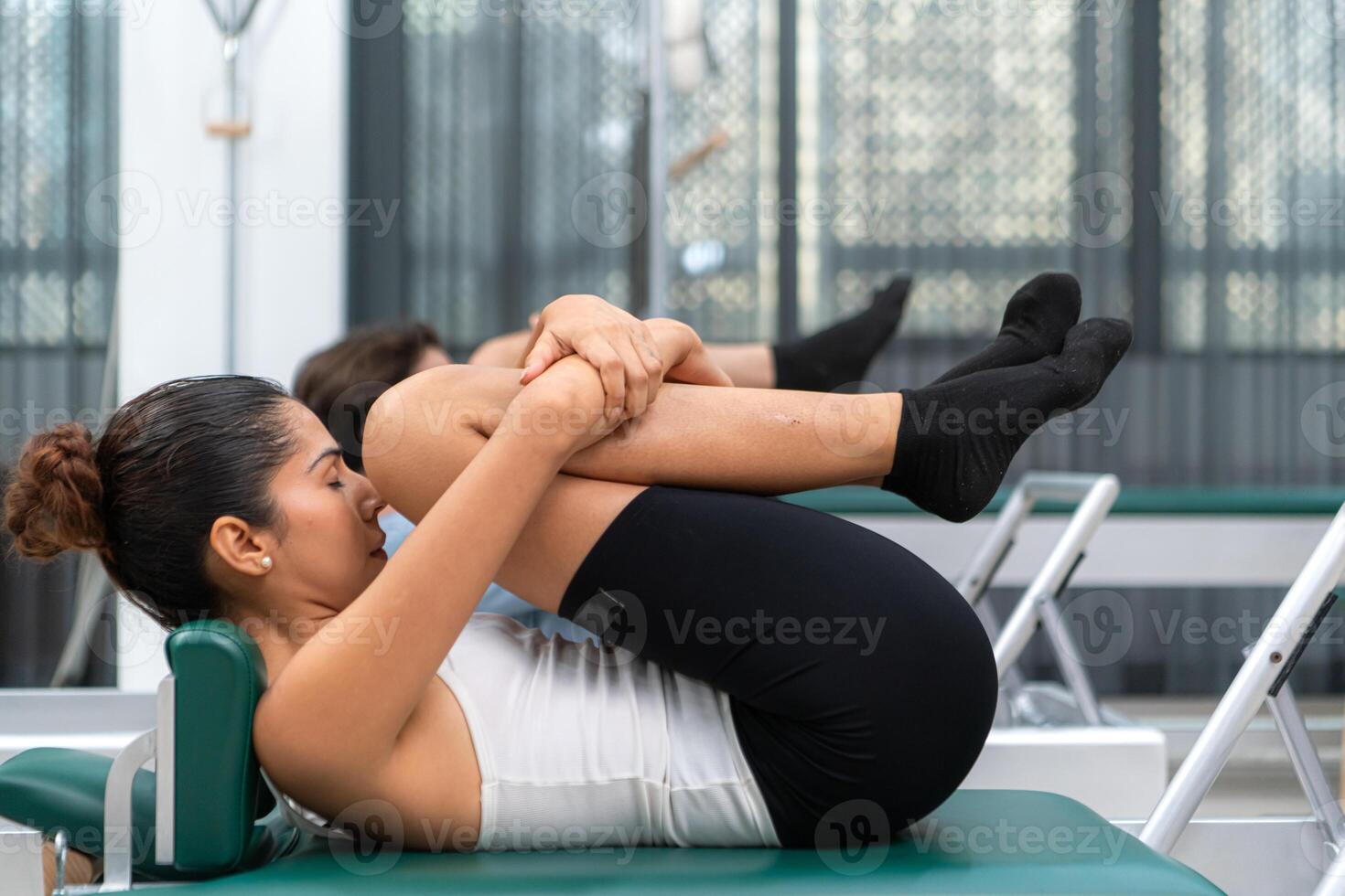 A young man and a young woman are doing pilates exercises on a pilates reformer photo