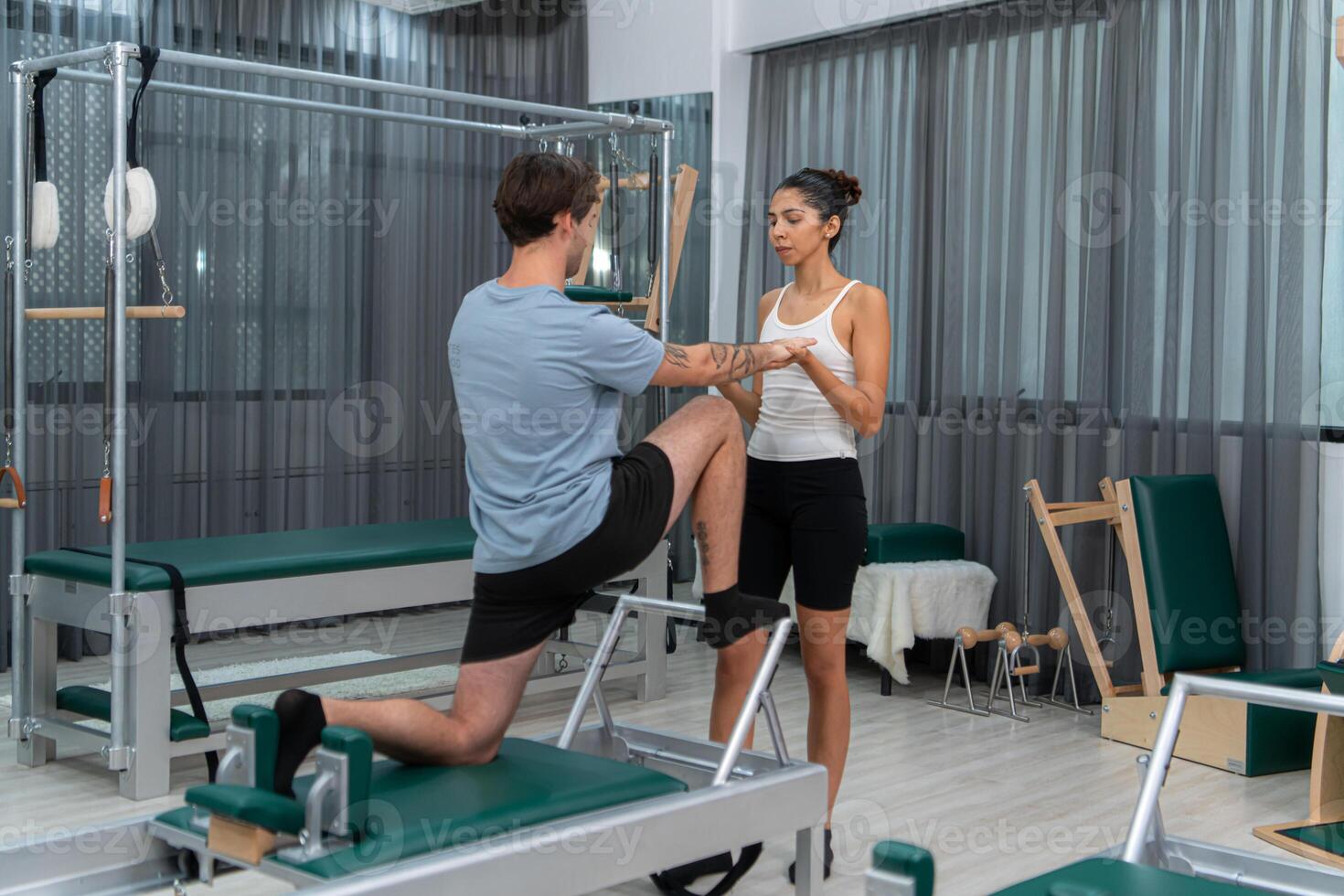 A young man and a young woman are doing pilates exercises on a pilates reformer photo
