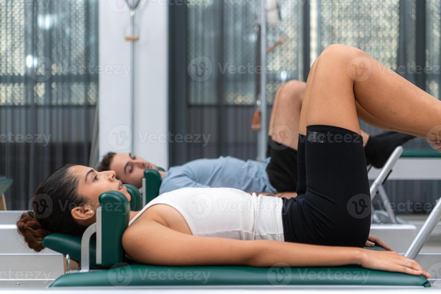 A young man and a young woman are doing pilates exercises on a pilates reformer photo