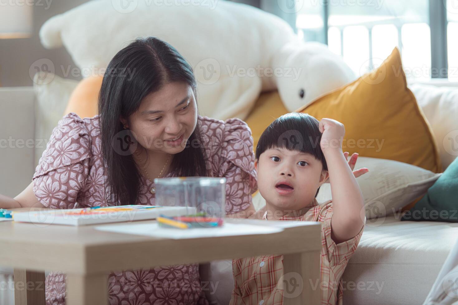 A special child with his mom paint and coloring together in the living room of the house photo