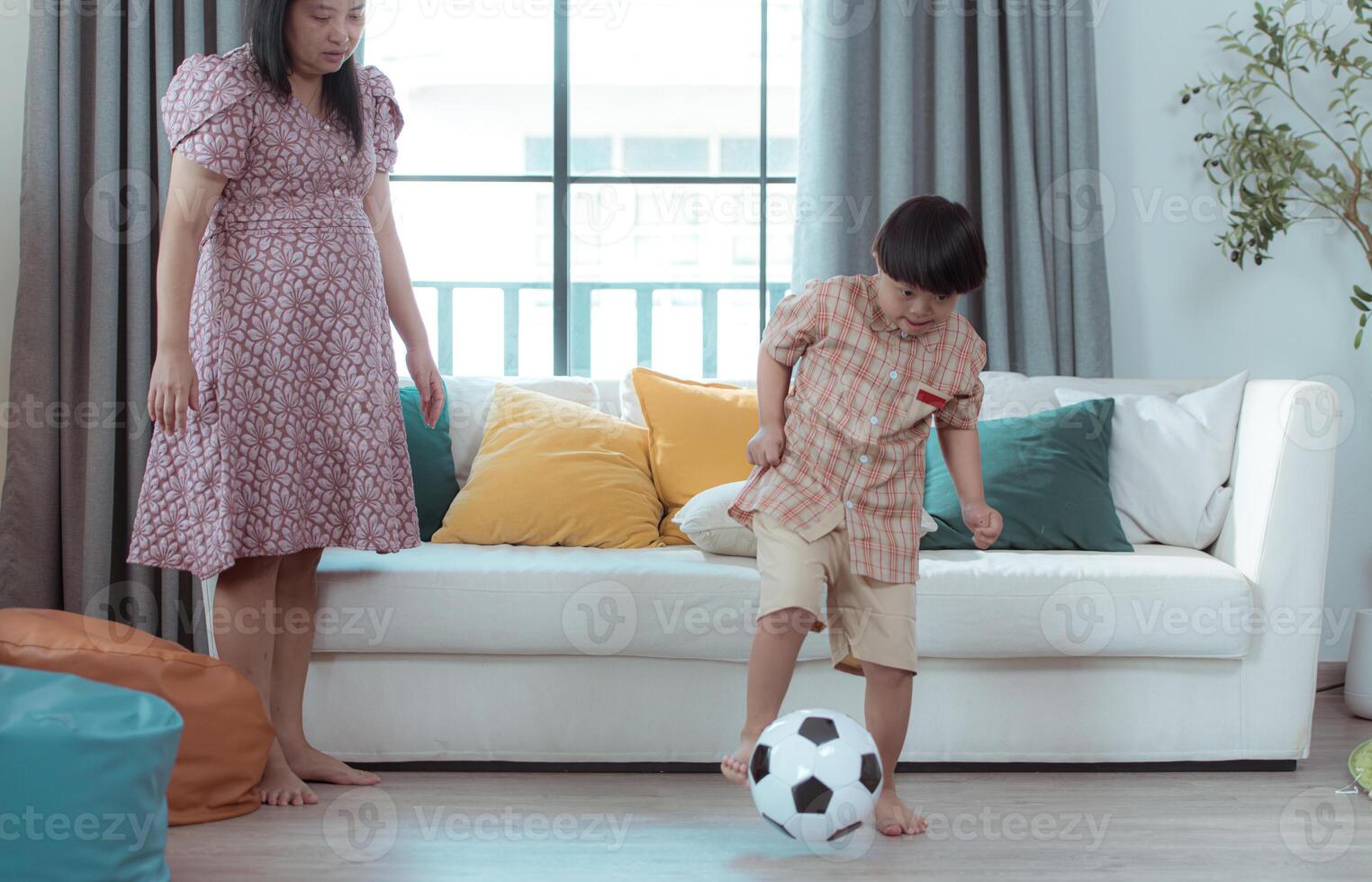 A special child with his mom playing soccer together in the living room of the house photo