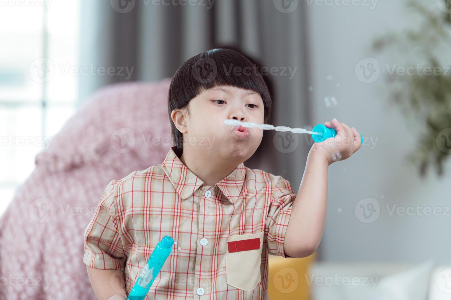 A special child with his mom having fun playing with a soap bubble bag in the living room of the house photo
