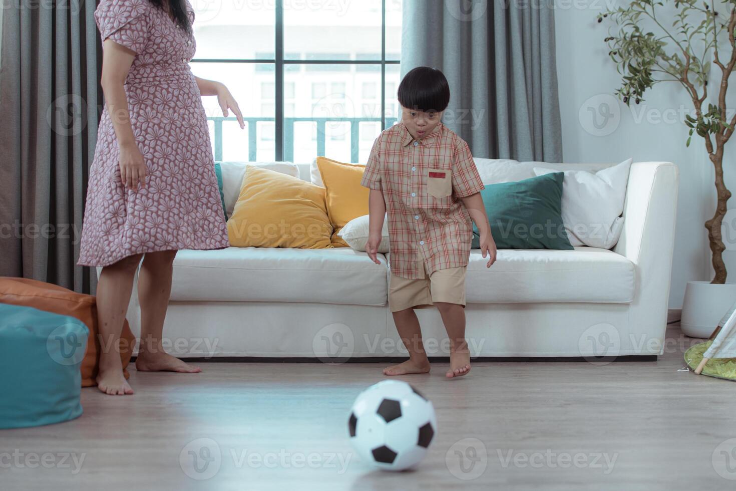 A special child with his mom playing soccer together in the living room of the house photo