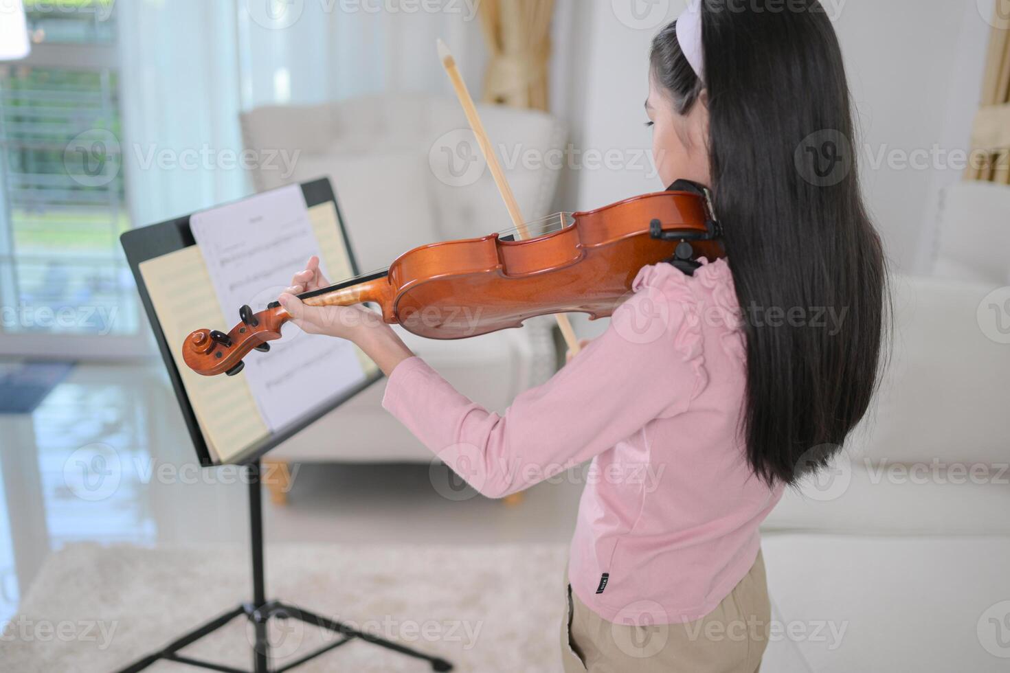 A girl violinist plays and practices the violin at home photo