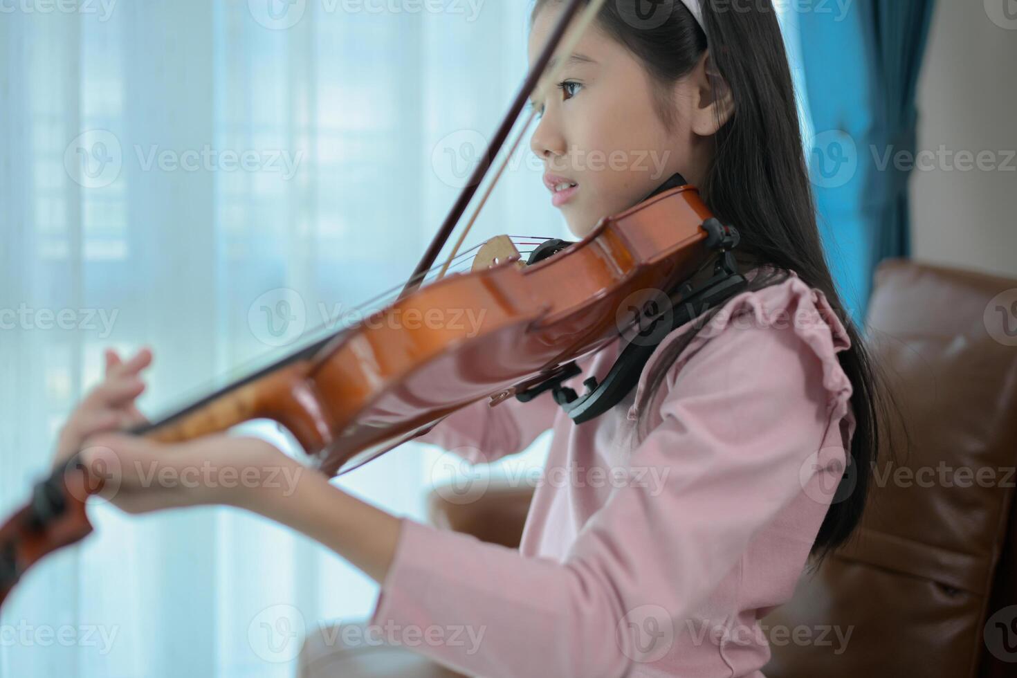 A girl violinist plays and practices the violin at home photo