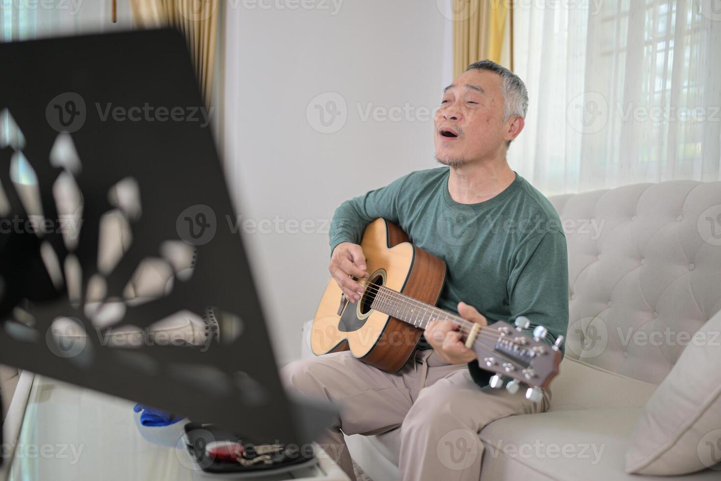 Senior man a veteran guitarist plays music at home photo