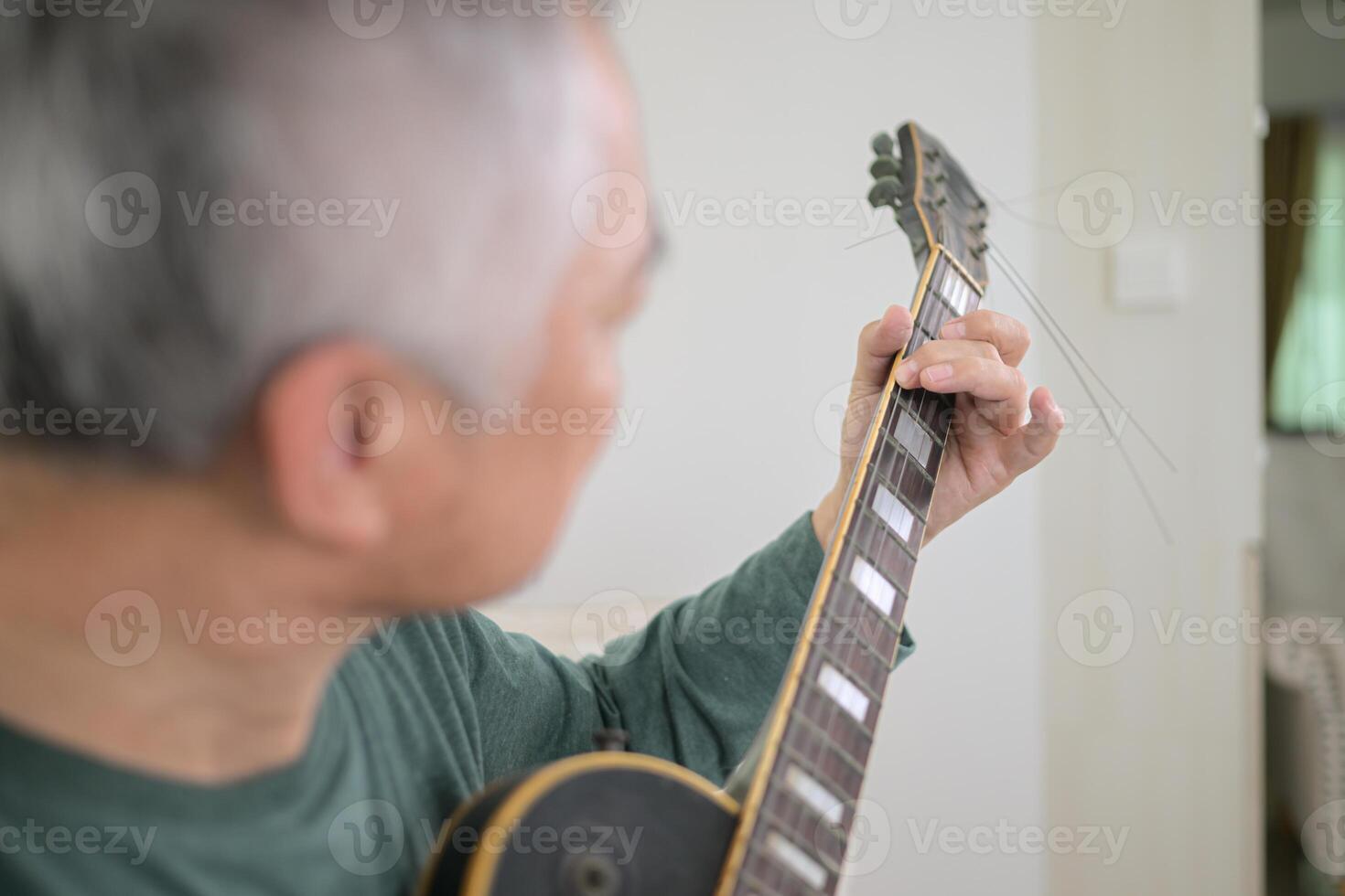 Senior man a veteran guitarist plays the old electric guitar at home photo