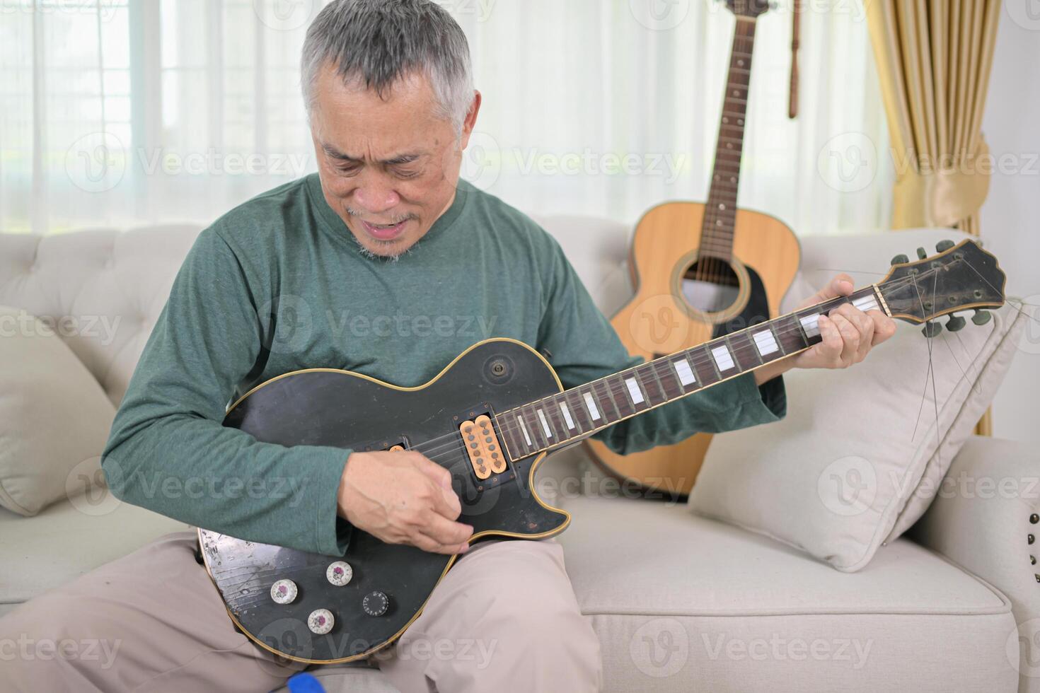 Senior man a veteran guitarist plays the old electric guitar at home photo