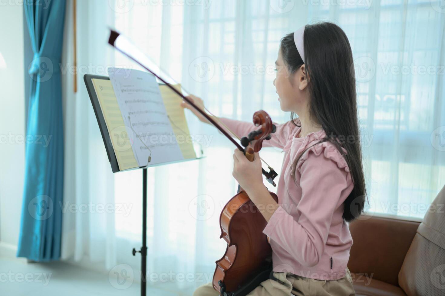 A girl violinist plays and practices the violin at home photo