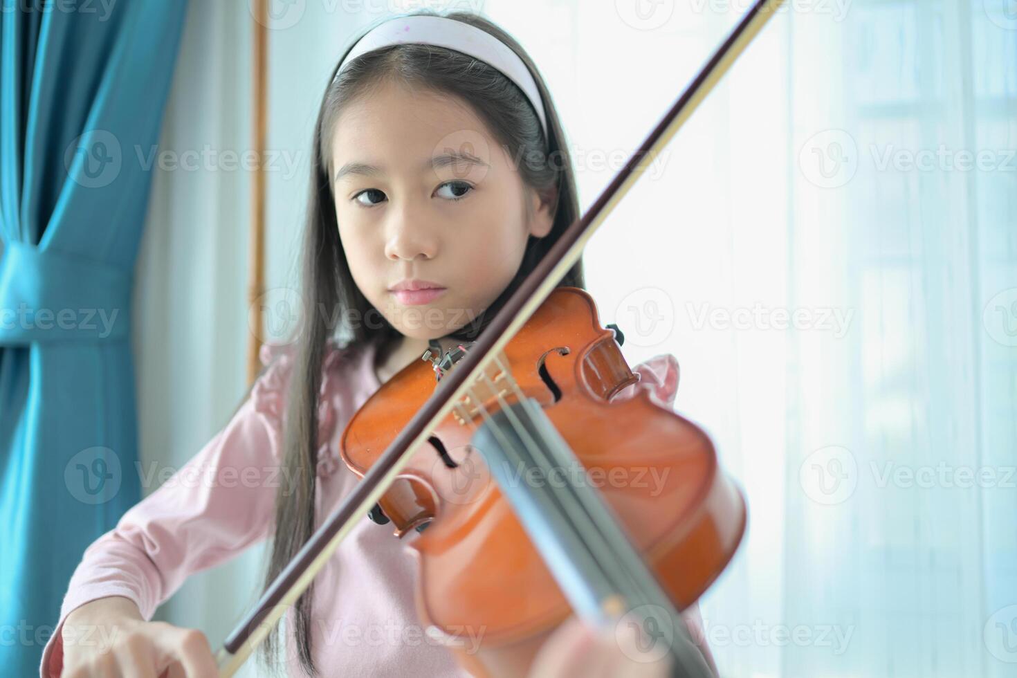 A girl violinist plays and practices the violin at home photo
