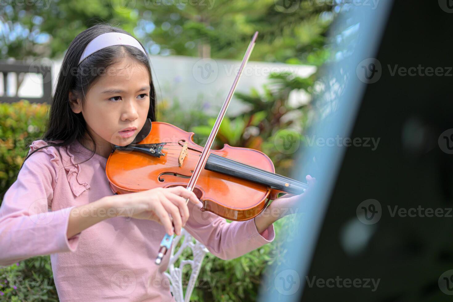 A girl violinist plays and practices the violin in the garden at home photo