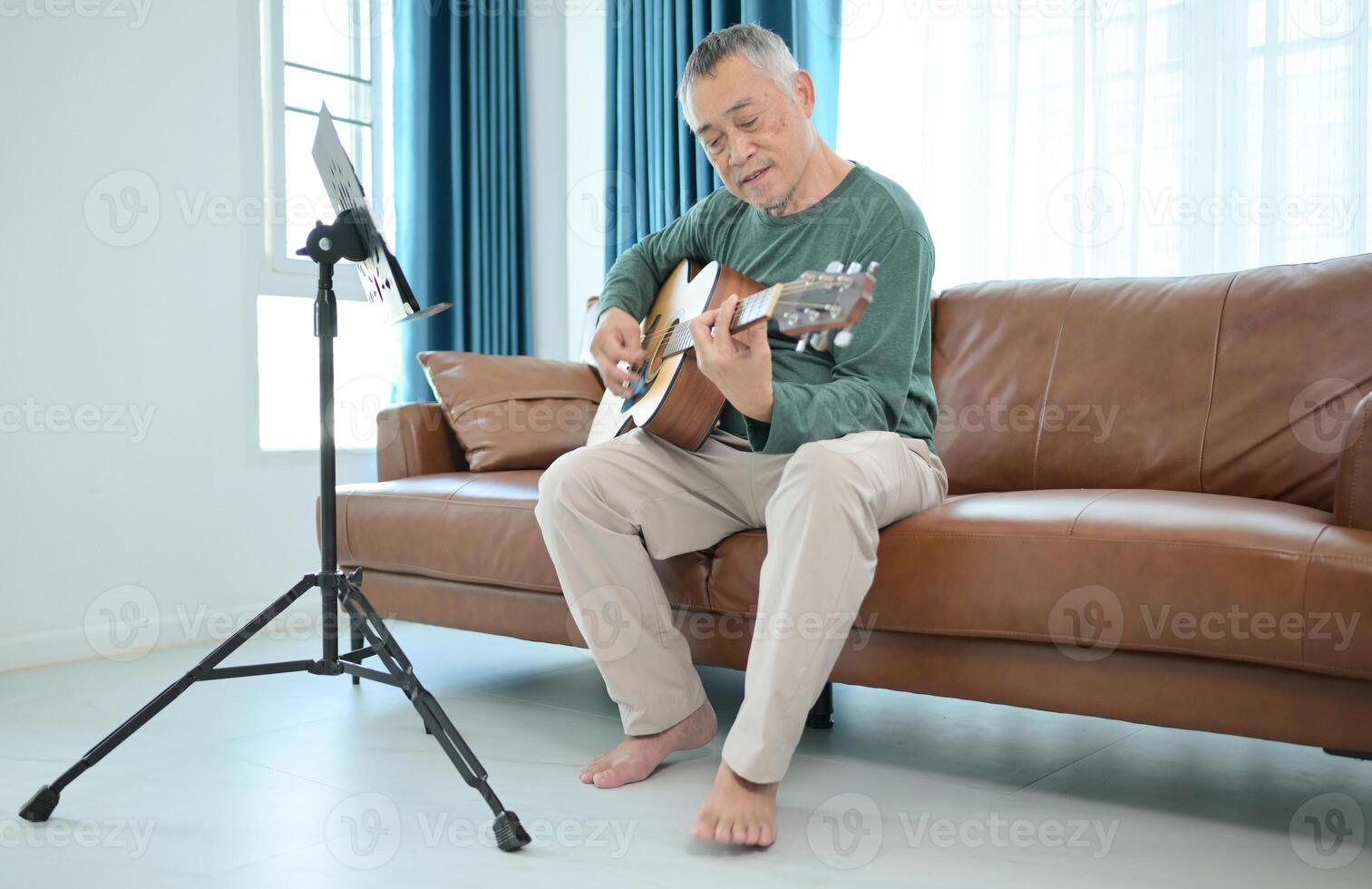 Senior man a veteran guitarist plays music at home photo
