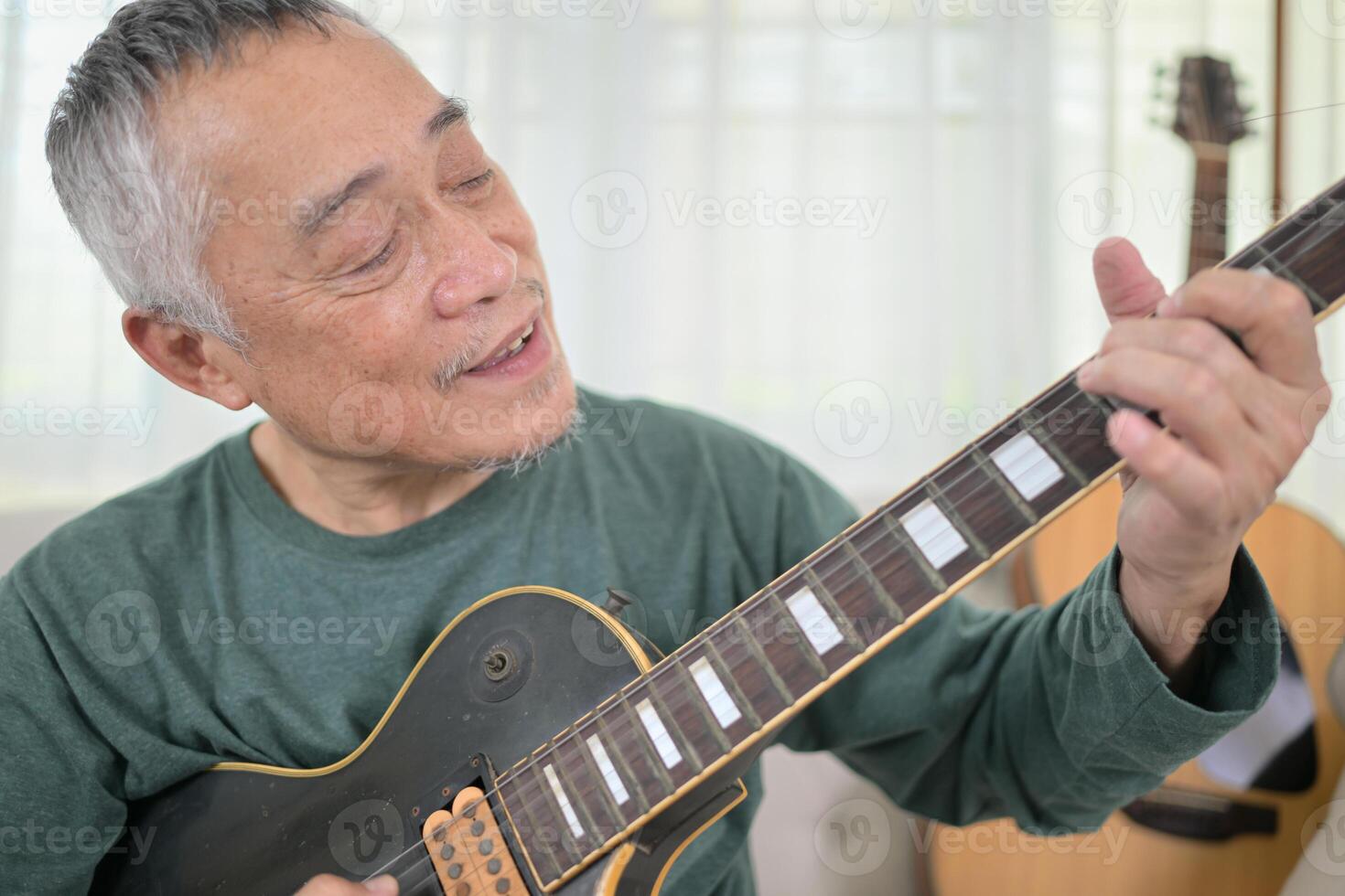 Senior man a veteran guitarist plays the old electric guitar at home photo