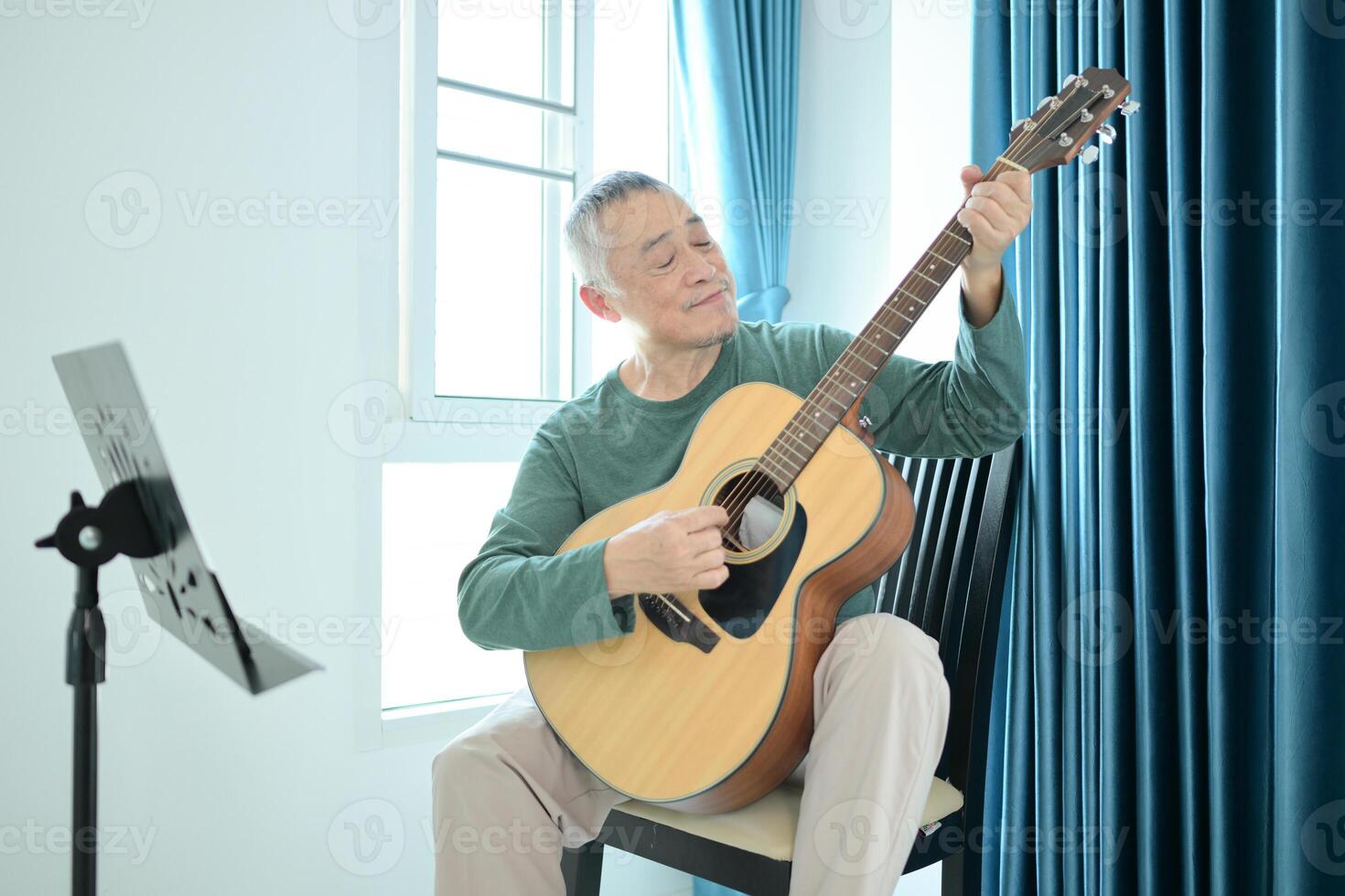 Senior man a veteran guitarist plays music at home photo