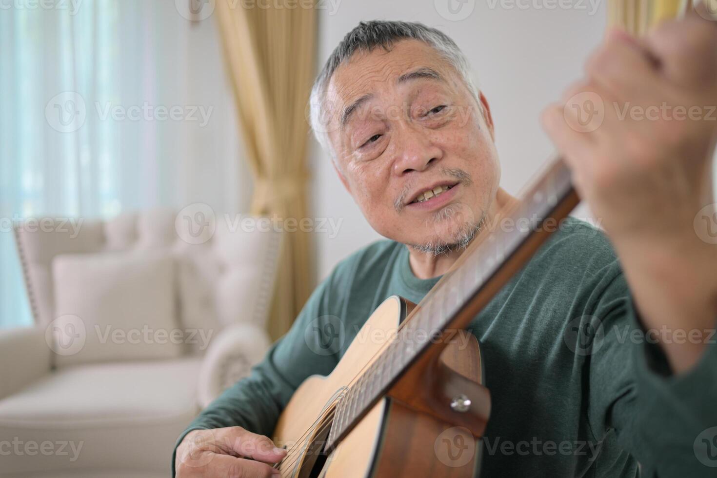 Senior man a veteran guitarist plays music at home photo