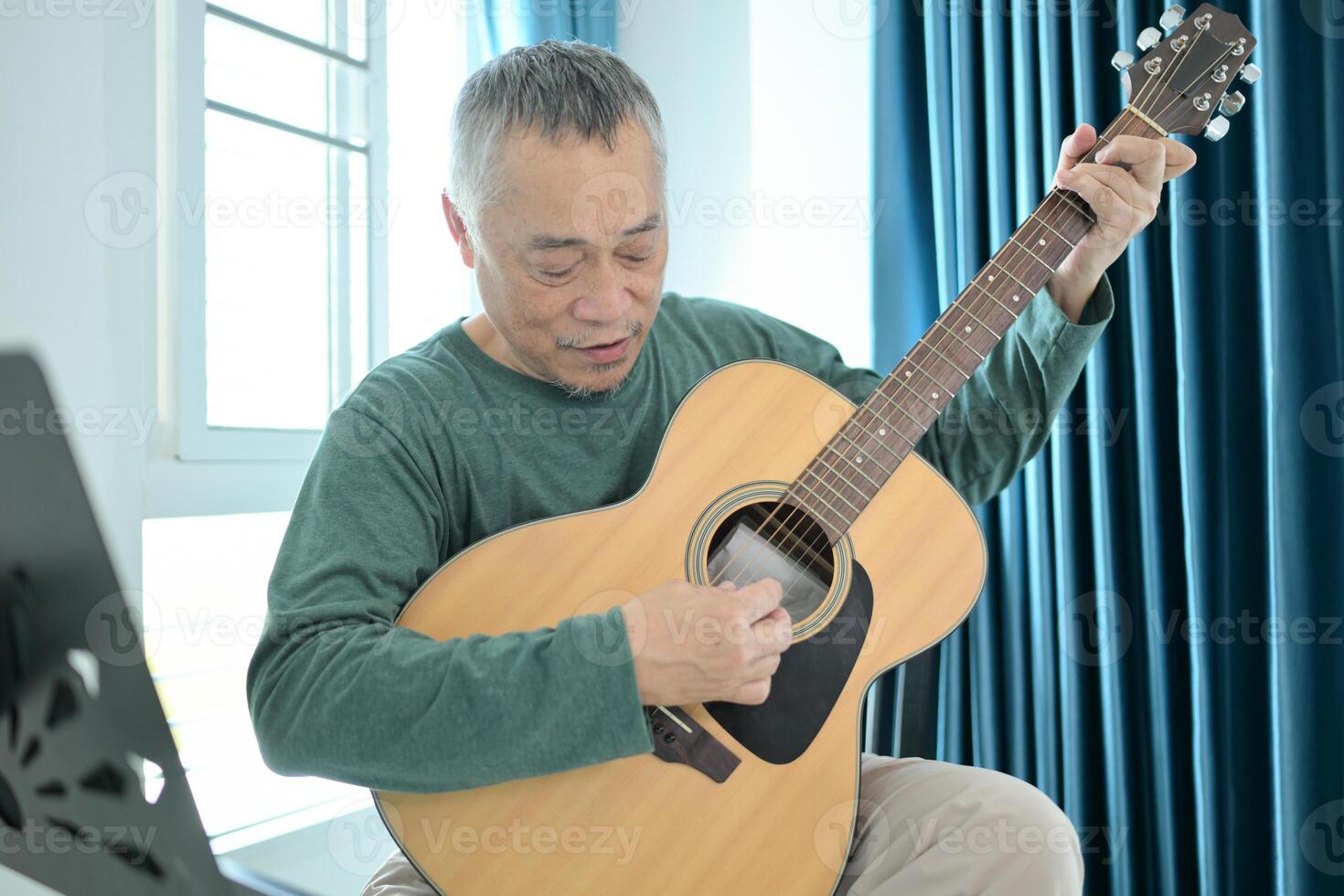 Senior man a veteran guitarist plays music at home photo