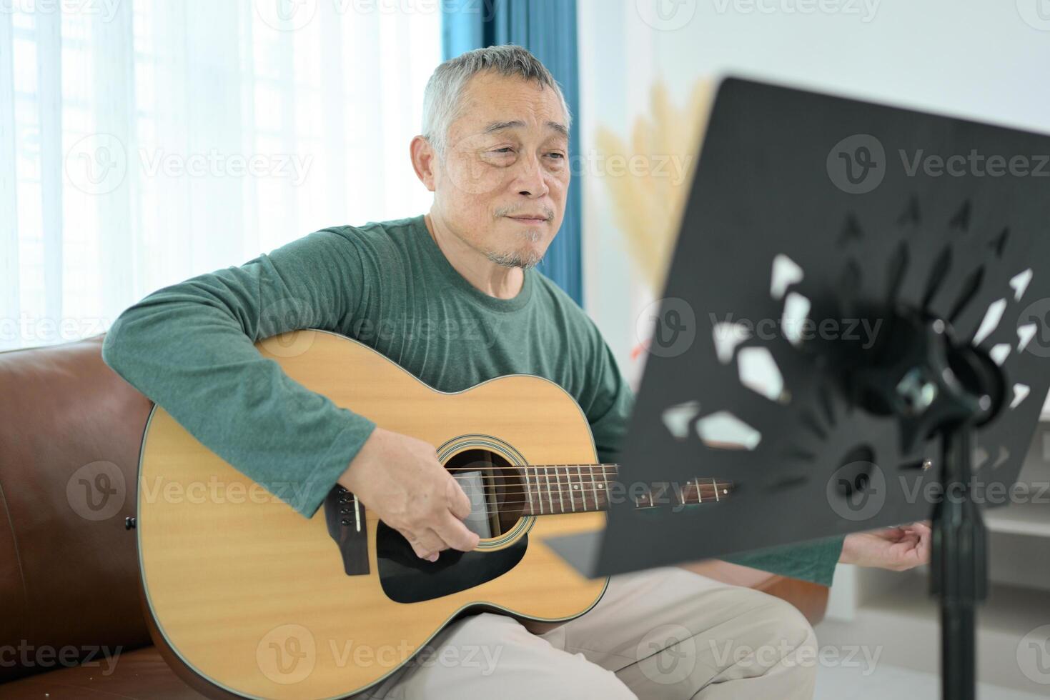 Senior man a veteran guitarist plays music at home photo