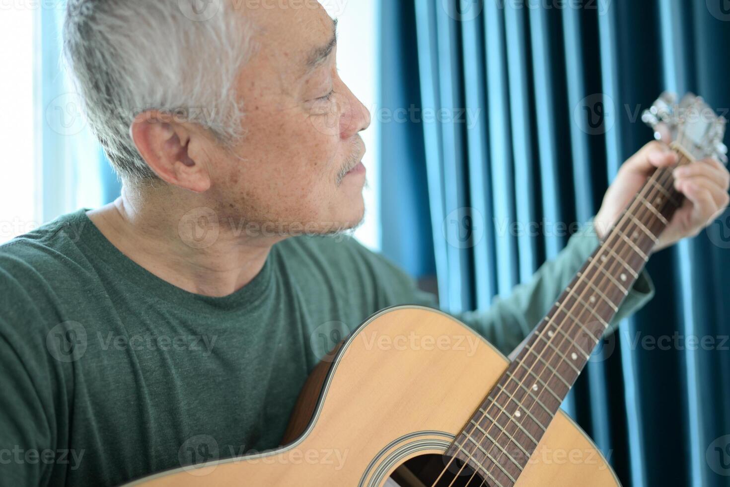 Senior man a veteran guitarist plays music at home photo