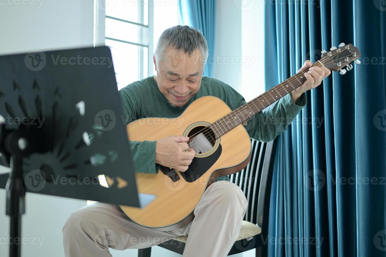 Senior man a veteran guitarist plays music at home photo