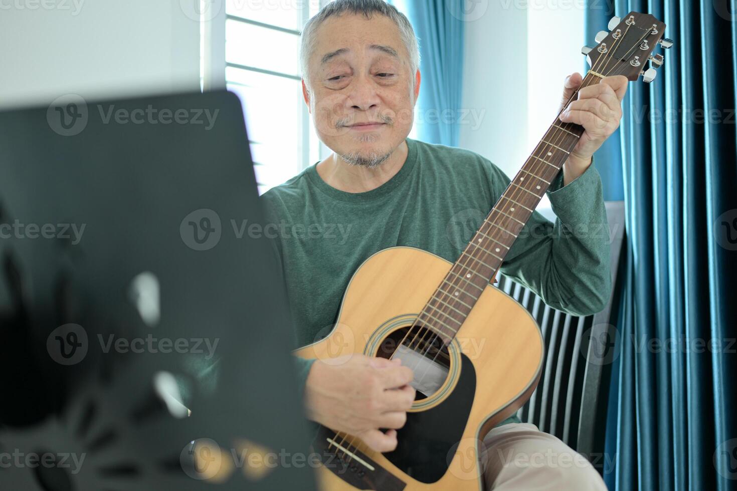 Senior man a veteran guitarist plays music at home photo
