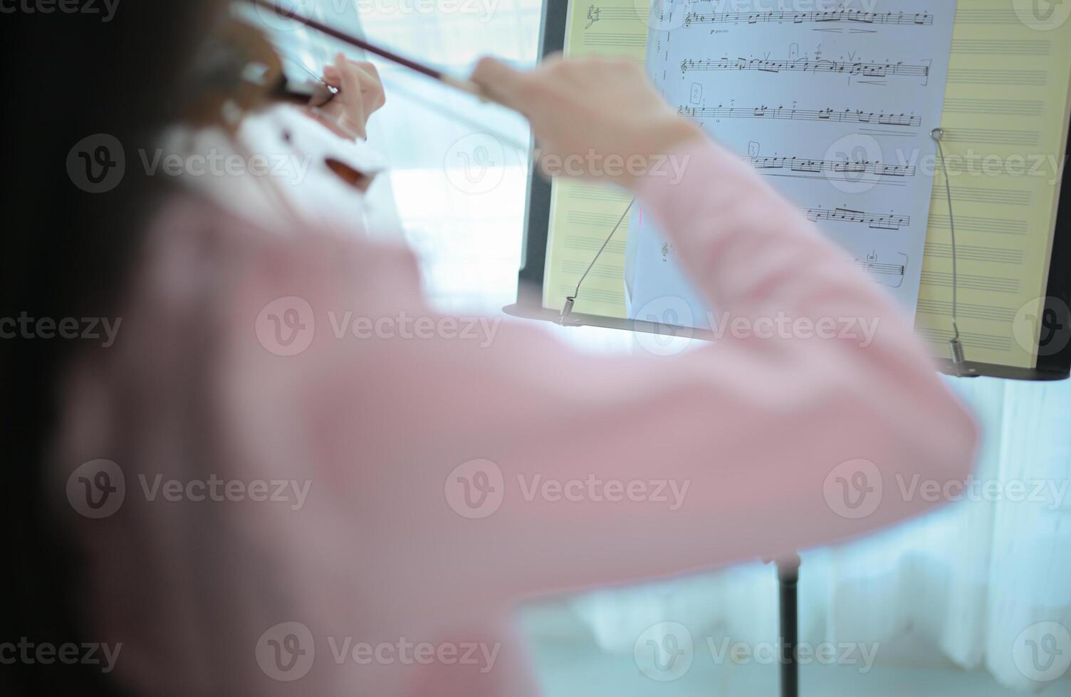 A girl violinist plays and practices the violin at home photo