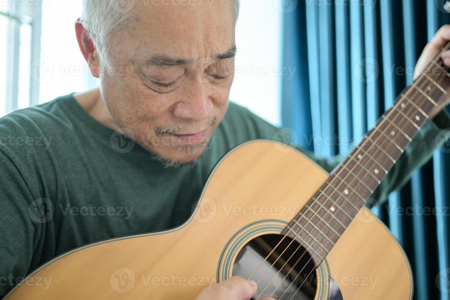 Senior man a veteran guitarist plays music at home photo