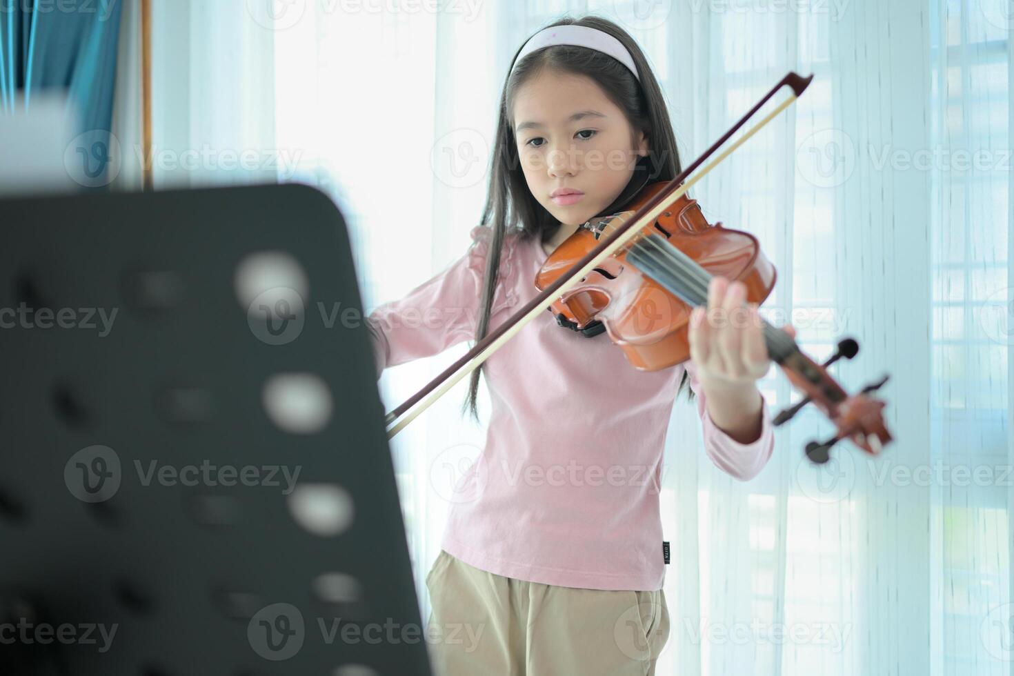A girl violinist plays and practices the violin at home photo