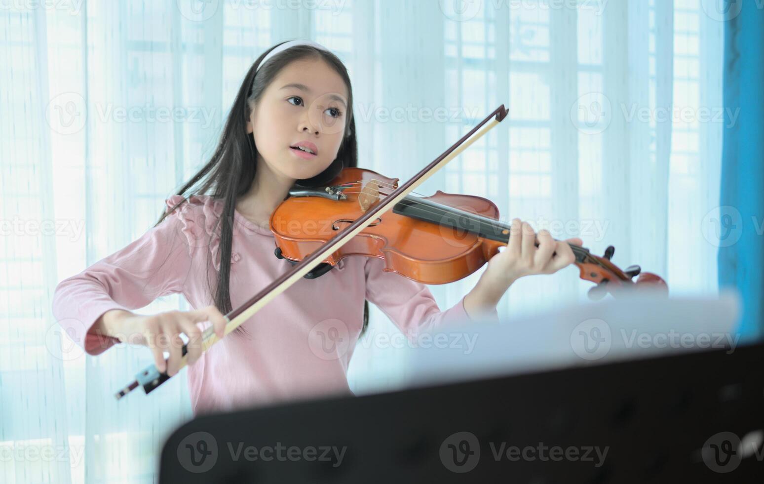 A girl violinist plays and practices the violin at home photo